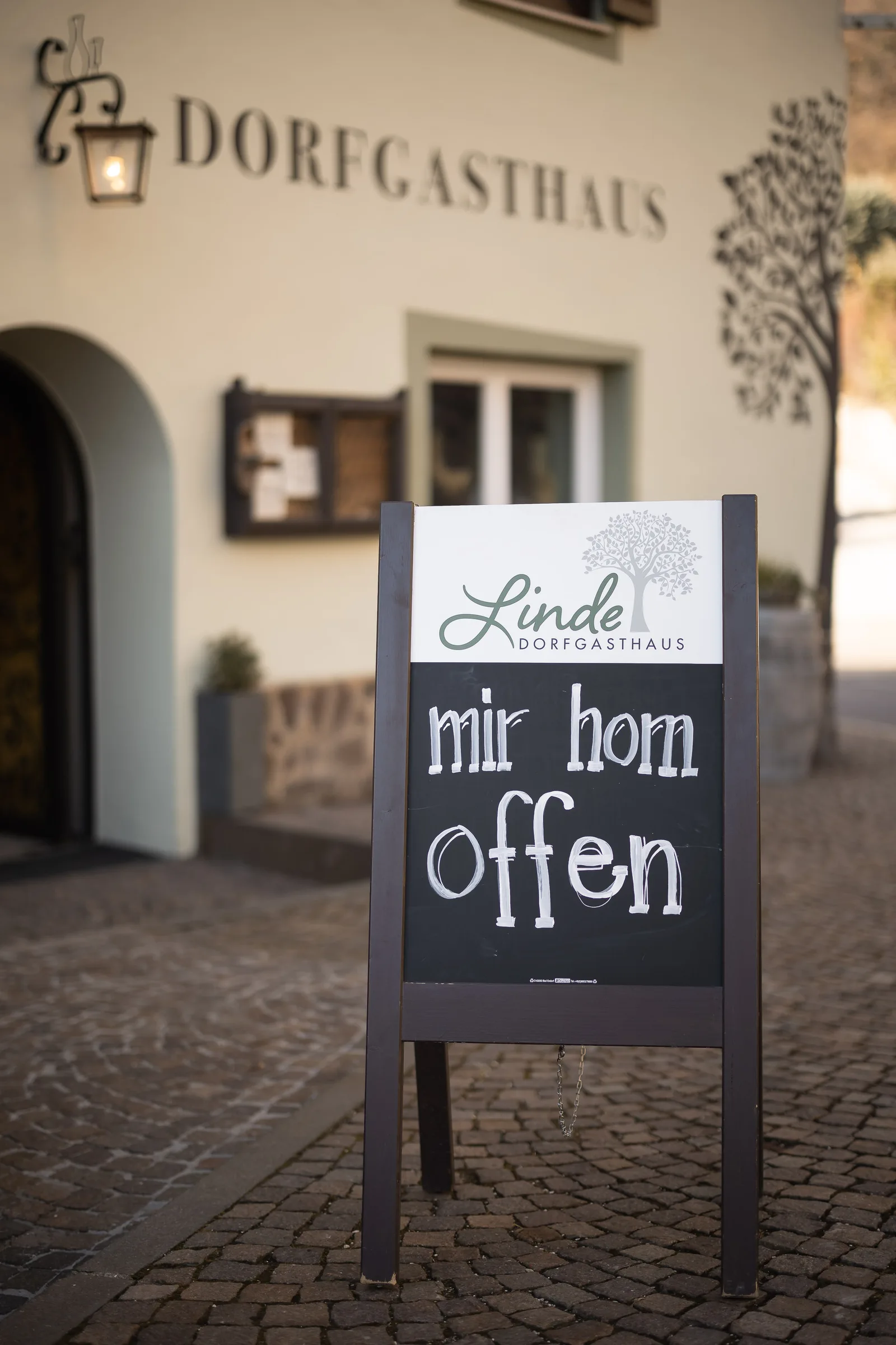 A board reading “mir hom offen”, dialect for “we are open”, outside Dorfgasthaus zur Linde in Kaltern