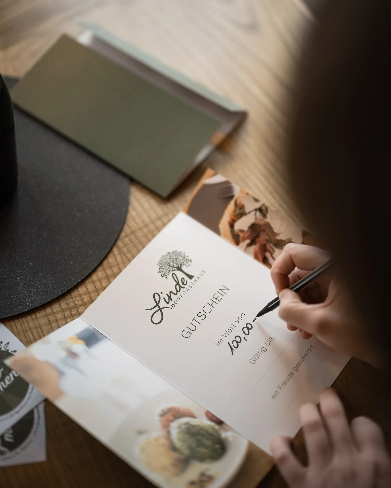 A gift voucher from Dorfgasthaus zur Linde being written out by hand at the table