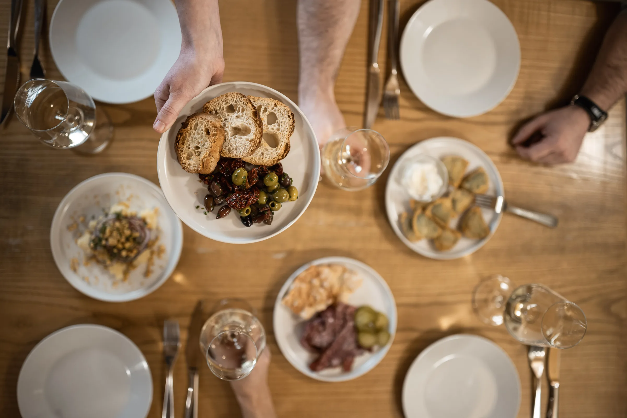 A laid table at Dorfgasthaus zur Linde seen from above, with a starter of bread and olives being served